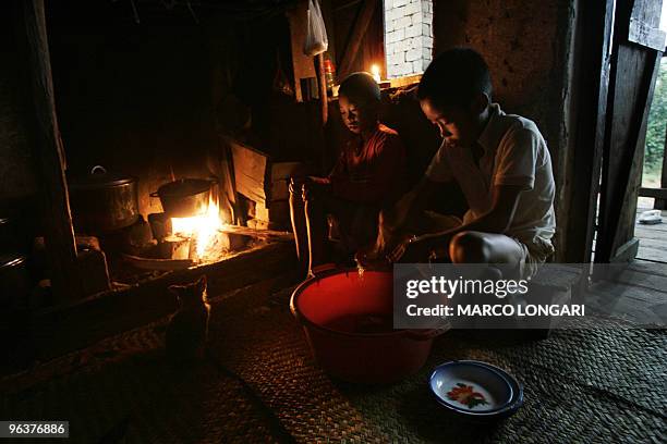 Manisa Ranarijaona washes up the dishes for the breakfast which is cooking on the fire at 05:00am, while his younger brother looks on 05 December...