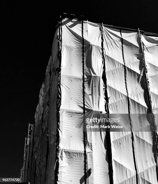 detail of corner of commercial building wrapped in white material to hide construction renovation with bright blue sky - blue corner stockfoto's en -beelden