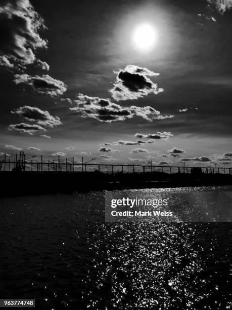black and white view of lower manhattan skyline and east river, new york harbor shot form brooklyn riverfront. dramatic cloudscape sky - silbertreifen am horizont stock-fotos und bilder