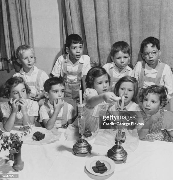 Jewish children lighting the two Shabbat candles on a friday in Israel, circa 1955.