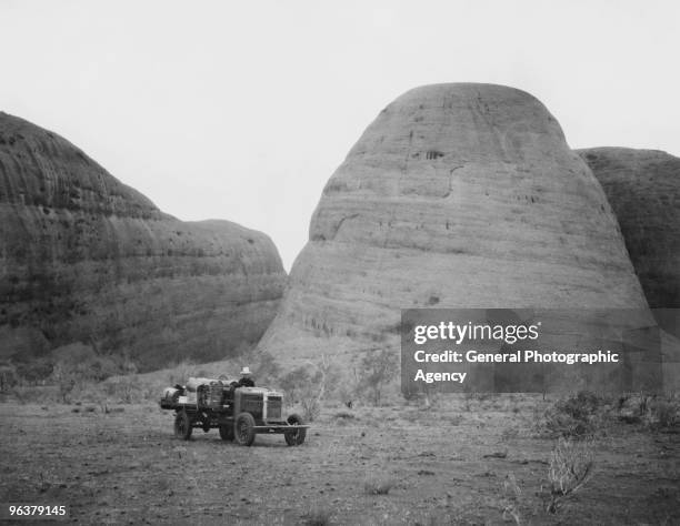 Truck parked at the base of Ayers Rock , a large sandstone rock formation in the Northern Territory, Australia, circa 1935.