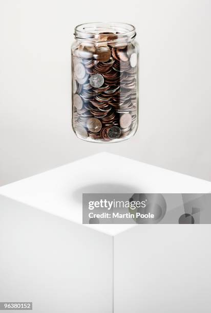 jar of coins floating above white block - martin poole stock pictures, royalty-free photos & images