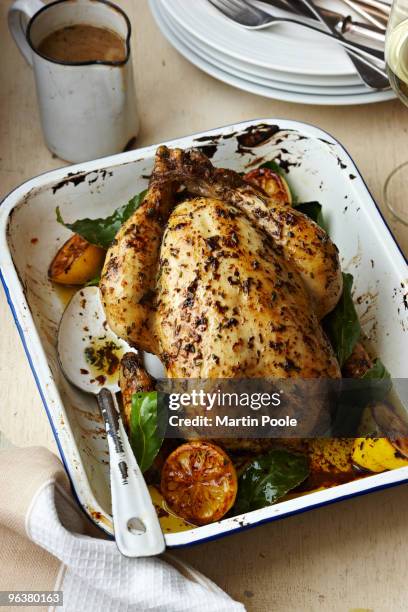 roast chicken in baking tray on table - roast chicken table stockfoto's en -beelden