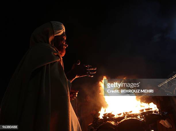 Pakistani Muslim Sufi bangs prays around a fire next to the Data Darbar where is the Saint Syed Ali bin Osman Al-Hajvery shrine, popularly known as...