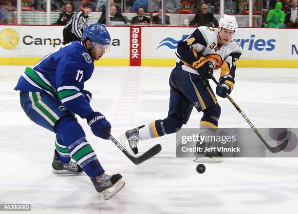 Ryan Kesler of the Vancouver Canucks and Chris Butler of the Buffalo Sabres watch a loose puck during their game against the Vancouver Canucks at...