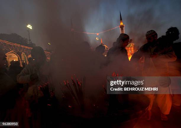 Pakistani Muslim devotees burn insence sticks and pray inside the Data Darbar where is the Saint Syed Ali bin Osman Al-Hajvery shrine, popularly...