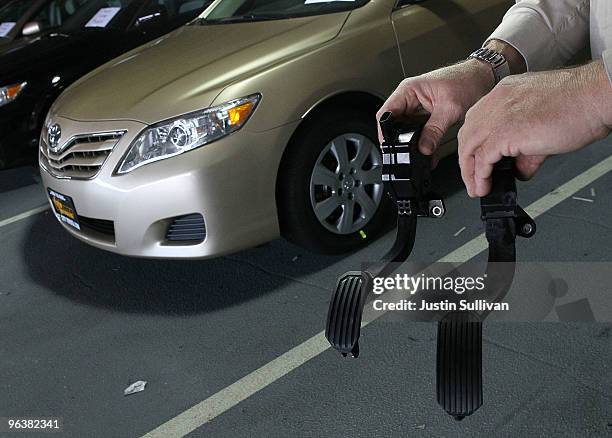 City Toyota service manager Jim Lasseter holds a recalled accelerator pedal and the new modified part next to a brand new Toyota Camry that is...