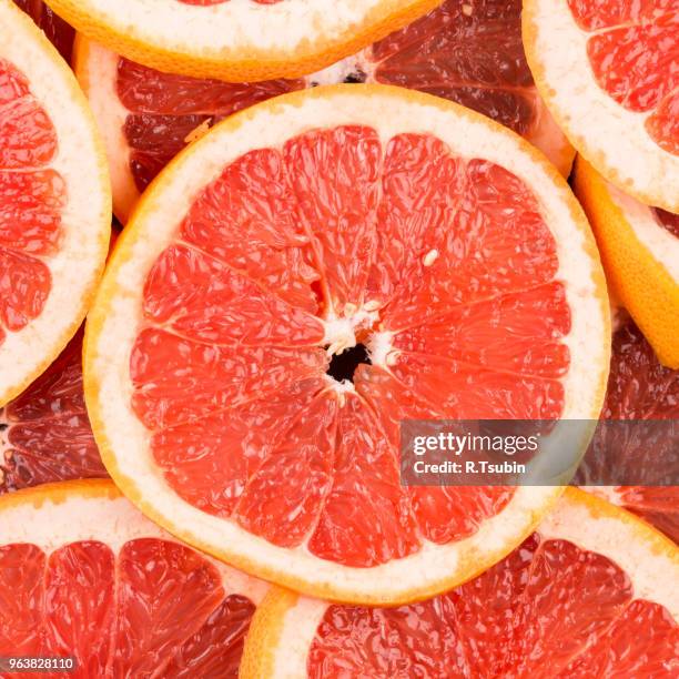 abstract red background with citrus-fruit of grapefruit slices. close-up - grapefruit stock pictures, royalty-free photos & images