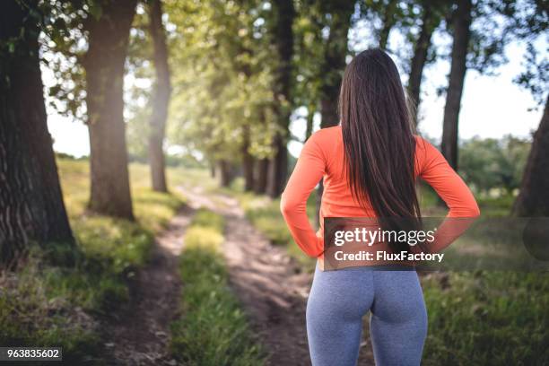 fit frau in leggins auf einem waldweg - buttock stock-fotos und bilder