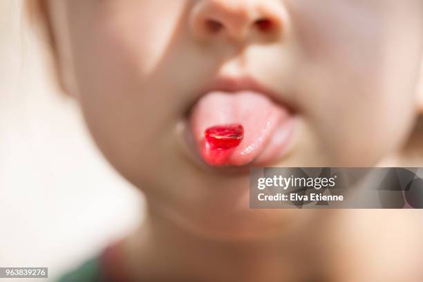 girl with red gummy sweet on the tip of her tongue - bonbon stock-fotos und bilder