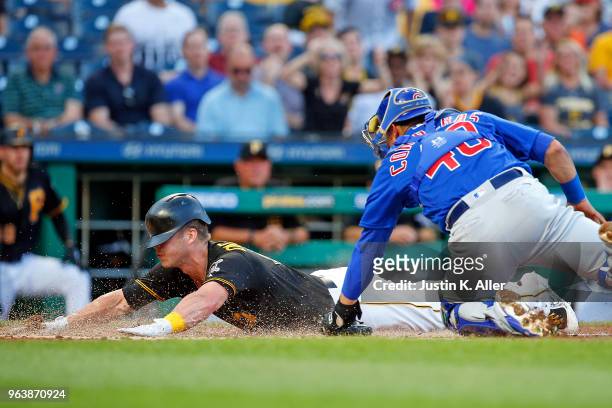 Corey Dickerson of the Pittsburgh Pirates scores on a sacrifice fly in the second inning against Willson Contreras of the Chicago Cubs at PNC Park on...
