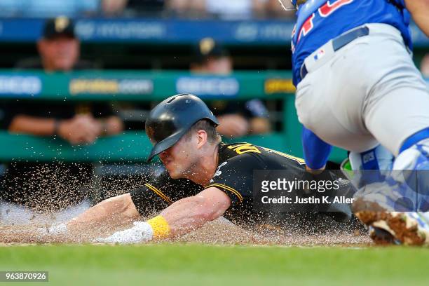 Corey Dickerson of the Pittsburgh Pirates scores on a sacrifice fly in the second inning against Willson Contreras of the Chicago Cubs at PNC Park on...