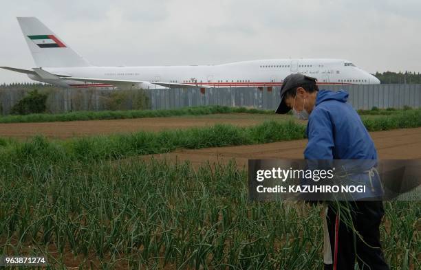 This picture taken on April 12, 2018 shows a farmer working on a farm beside a runway of Narita airport, Tokyo's main international gateway, in Chiba...