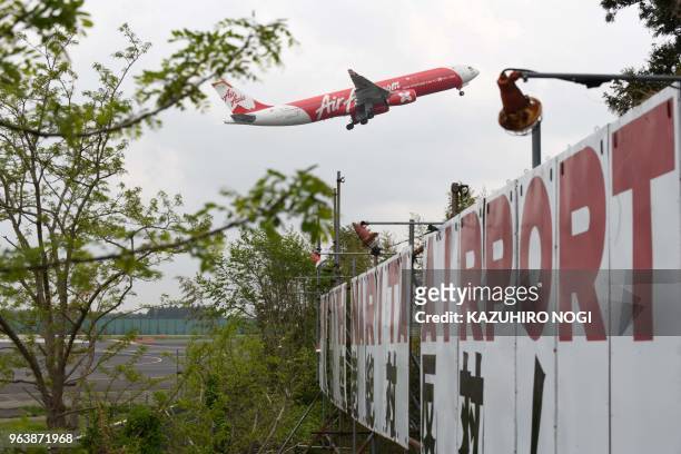 This picture taken on April 12, 2018 shows an airplane taking off over a protest board against runway construction at a farmland encircled by Narita...