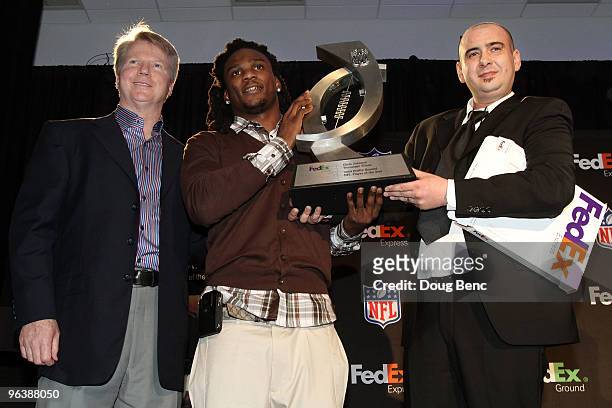 Chris Johnson of the Tennessee Titans holds his trophy after being named FedEx Ground NFL Player of the Year while alongside former NFL quarterback...