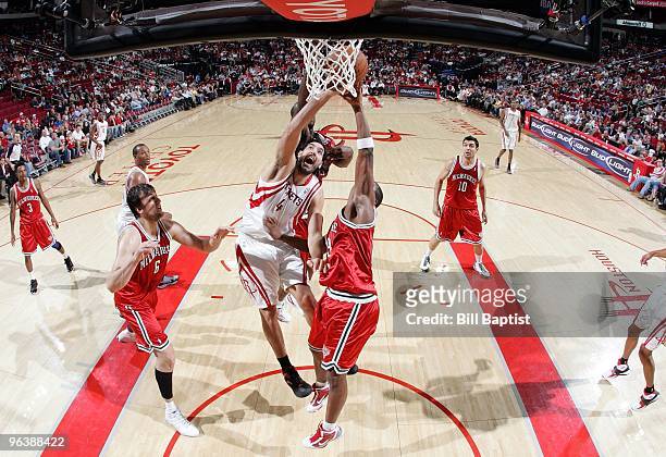 Luis Scola of the Houston Rockets goes up for a shot against Andrew Bogut and Jodie Meeks of the Milwaukee Bucks during the game at Toyota Center on...