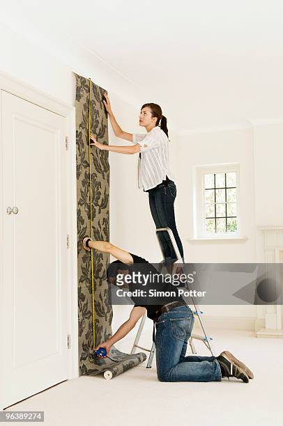 a couple putting up wallpaper - papel de parede - fotografias e filmes do acervo