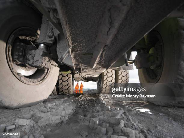 view of coal miners from under truck - baustellenfahrzeug stock-fotos und bilder