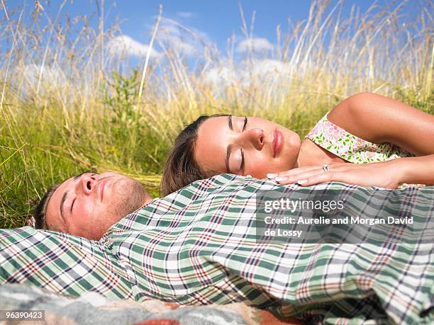 couple lying in field of high grasses - david de lossy sleep stock pictures, royalty-free photos & images