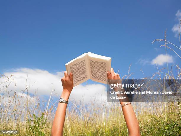 woman reading in field of high grasses - bücher lesen stock-fotos und bilder