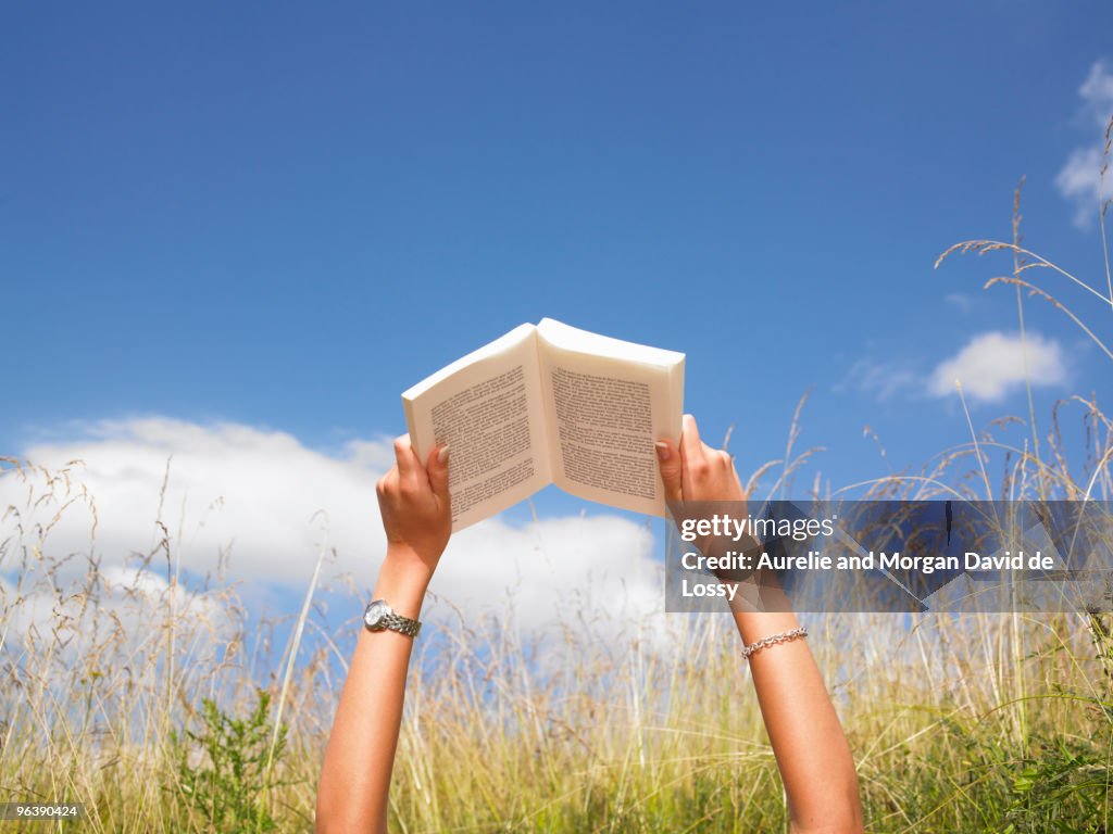 Woman reading in field of high grasses