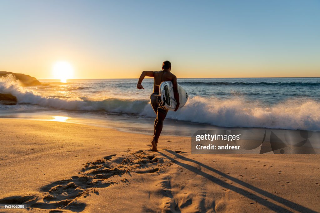 Surfer running into the water carrying his board