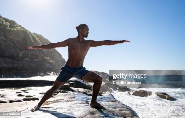 man doet yoga buiten door de zee - muscle men at beach stockfoto's en -beelden