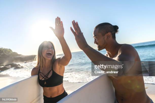 gelukkige paar van surfers op het strand een high-five te geven - muscle men at beach stockfoto's en -beelden