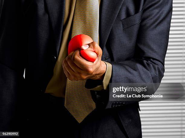 business man squeezing stress ball - squeezing stock pictures, royalty-free photos & images