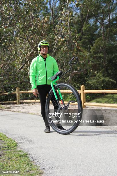 portrait of confident man holding unicycle - marie lafauci stock pictures, royalty-free photos & images