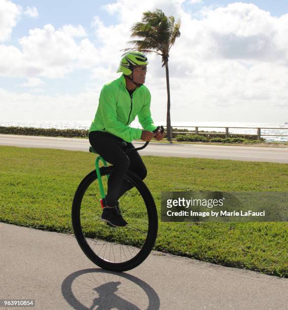 adult man riding a unicycle near the beach - unicycle stock pictures, royalty-free photos & images
