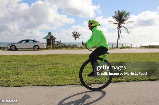 athletic man riding a unicycle near the beach - creepy shack stock pictures, royalty-free photos & images