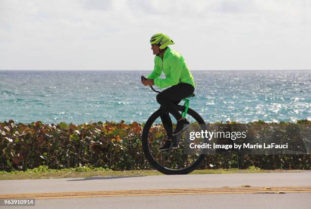 athletic man riding a unicycle near the beach - marie lafauci stock pictures, royalty-free photos & images