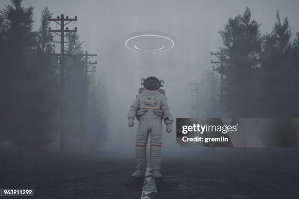 mysterieuze ufo en wandel astronaut op het bos weg bij nacht - verraad stockfoto's en -beelden