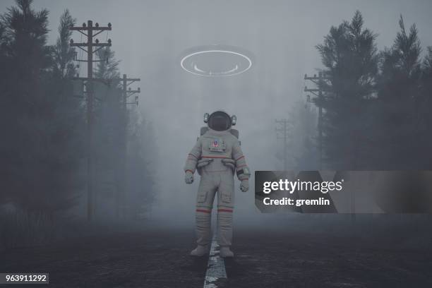 mysterious ufo and walking astronaut on the forest road at night - scheme stock pictures, royalty-free photos & images