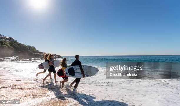 glückliche gruppe von freunden am strand surfen - surfer australia stock-fotos und bilder