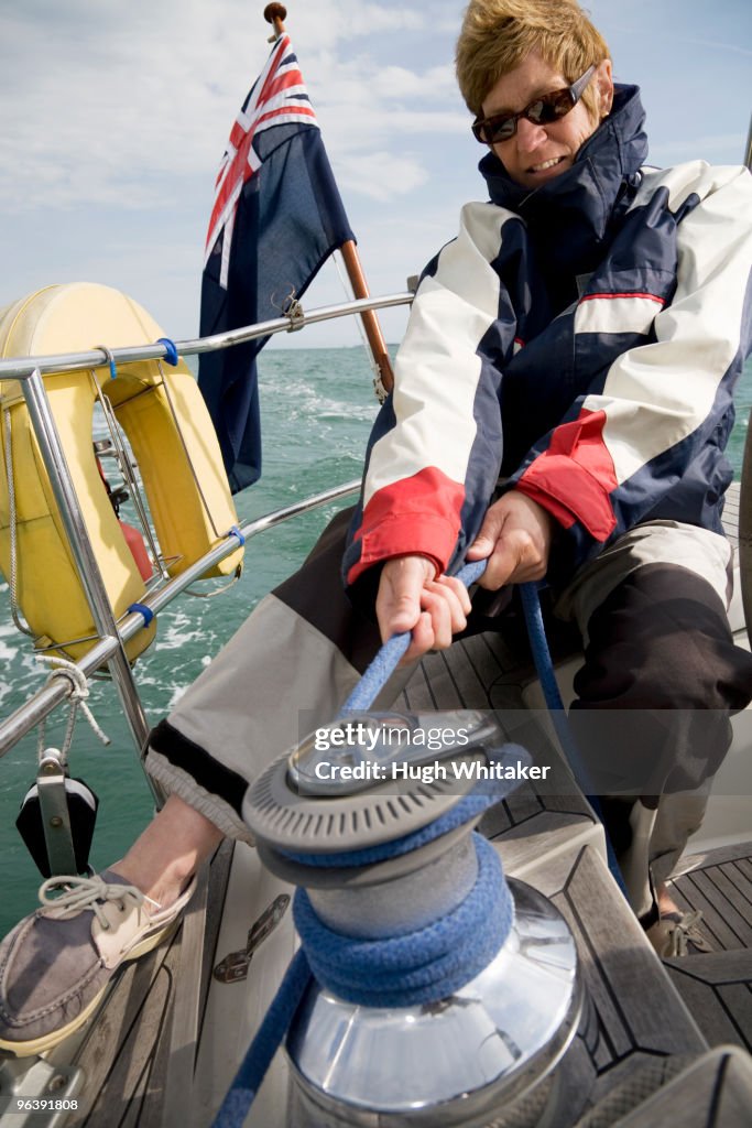 Woman hoisting sails on yacht