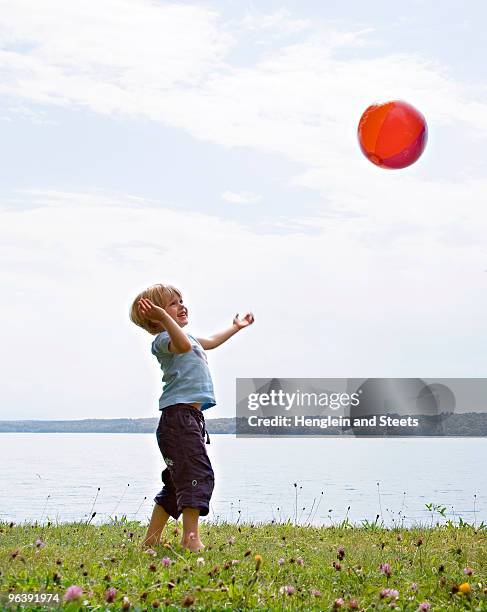 boy playing with ball at lake - kind im grundschulalter stock-fotos und bilder