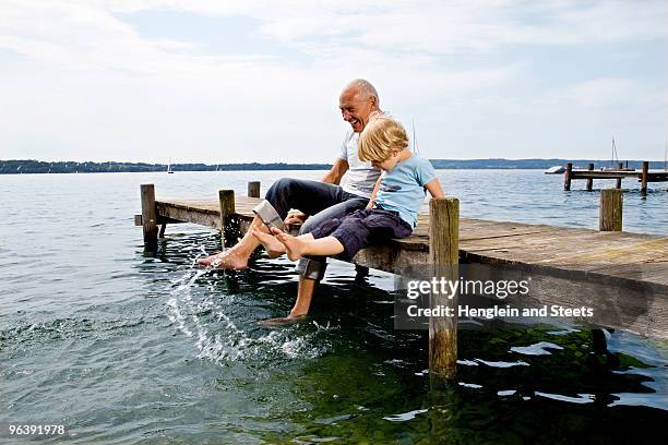 boy splashing with grandfather at lake - 家族　元気 ストックフォトと画像