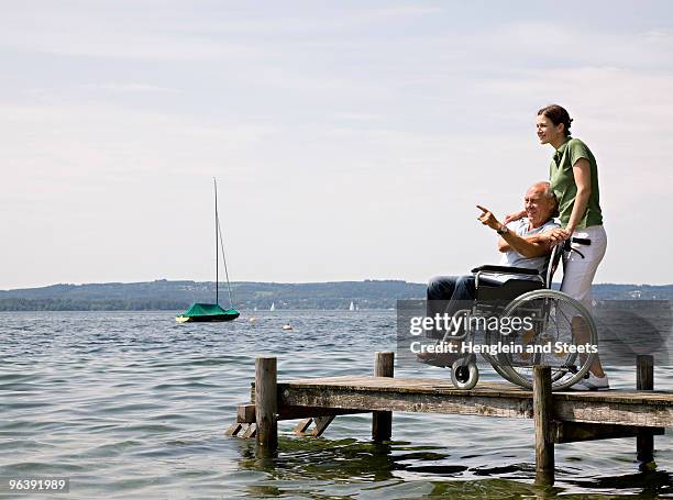 woman and senior man in wheelchair - boat side view stock pictures, royalty-free photos & images