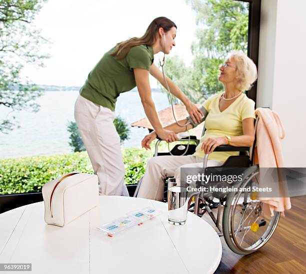 nurse taking woman's blood pressure - tablettenbox deutsch stock-fotos und bilder