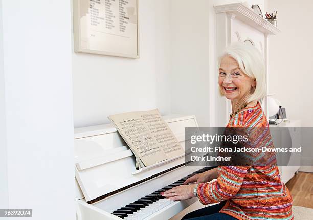 a senior female playing the piano - chelsea pensionär stock-fotos und bilder