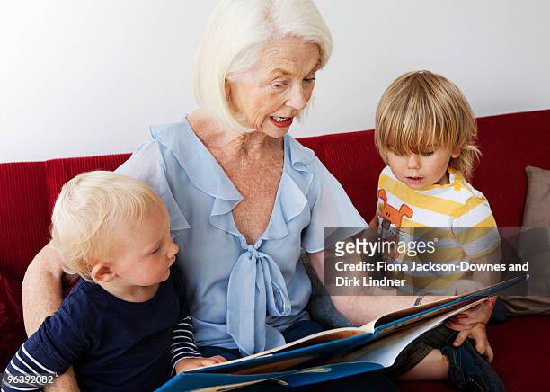 a grandmother reading to two toddlers - chelsea pensionär stock-fotos und bilder