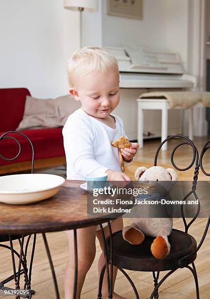 boy toddler at tea party with his teddy - baby eating toy foto e immagini stock