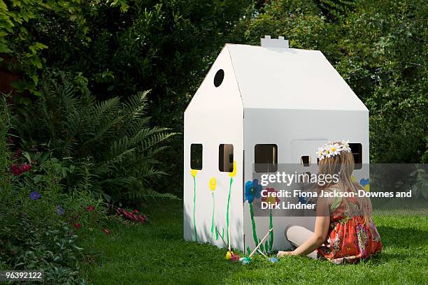 a girl painting a cardboard wendy house - playhouse stock-fotos und bilder