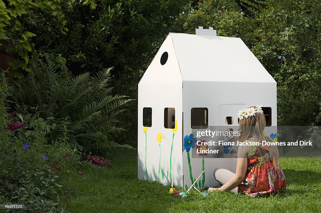 A girl painting a cardboard wendy house