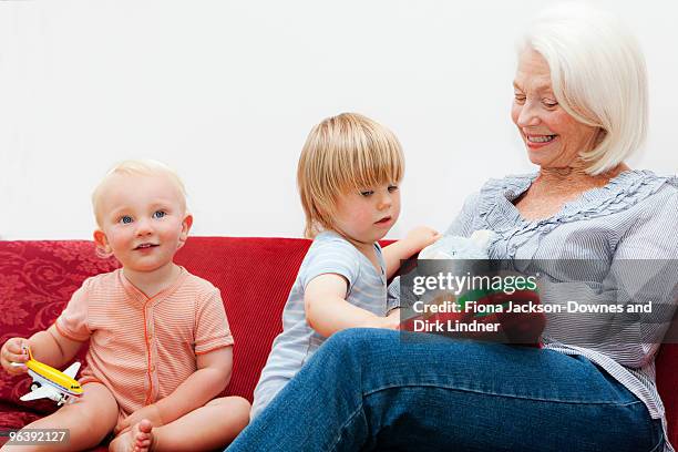 a grandmother playing with two toddlers - chelsea pensionär stock-fotos und bilder