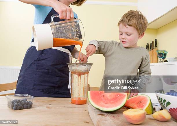 boy and mum making fruit smoothies - colander stockfoto's en -beelden
