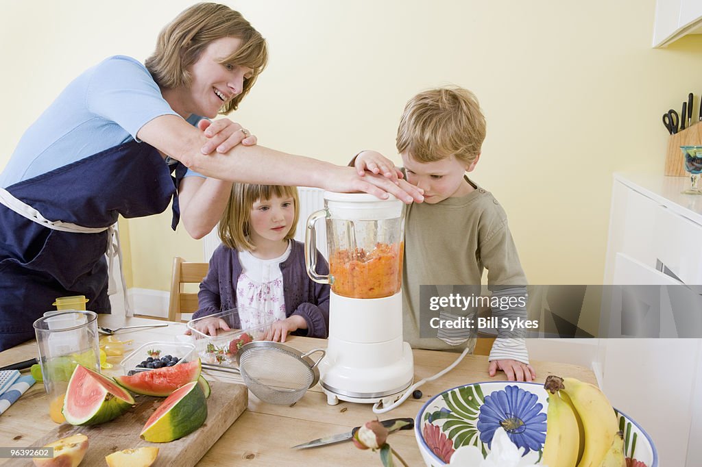 Boy, girl and mum making fruit smoothies