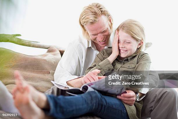 father and daughter reading a magazine - embarrased dad stock pictures, royalty-free photos & images
